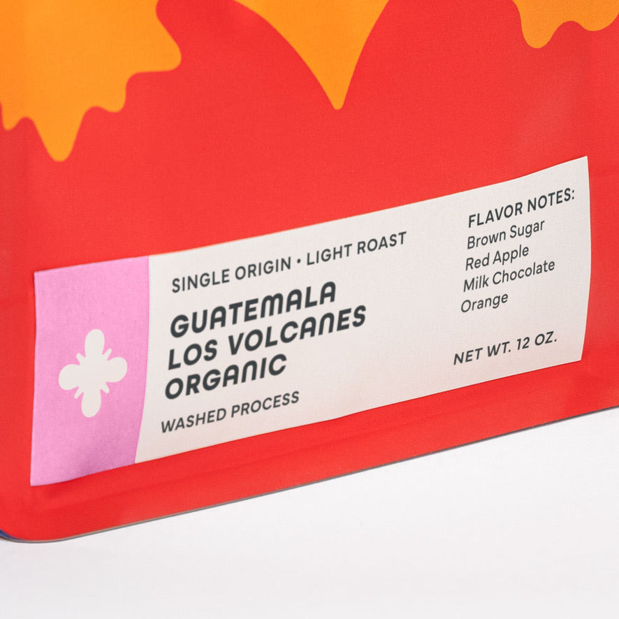 
                  
                    Close-up of the Guatemala Los Volcanes bag label with flavor notes brown sugar, red apple, milk chocolate, and orange.
                  
                