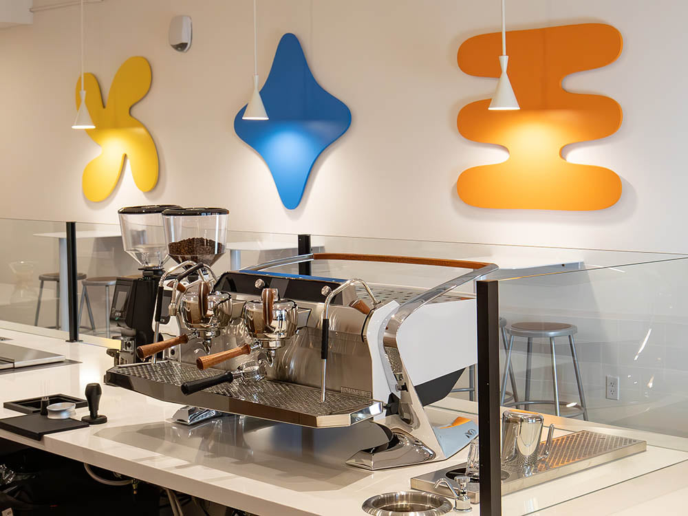Modern coffee shop interior with a coffee machine and colorful wall art.